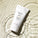 Tropic Face Smooth nourishing polish tube with macadamia nut oil, bamboo silica, and vitamin E, placed in rippling water for a refreshing look.